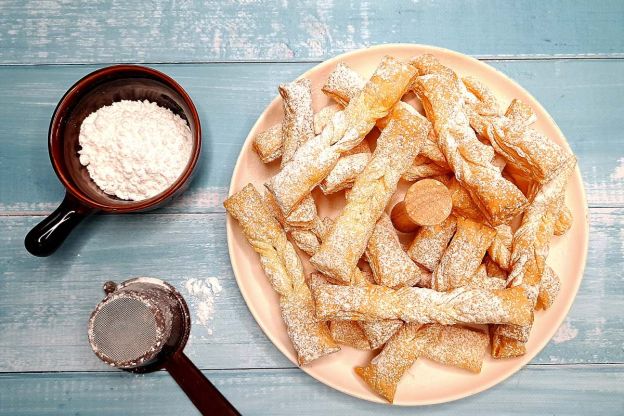 faworki z ciasta francuskiego - posypywanie cukrem pudrem