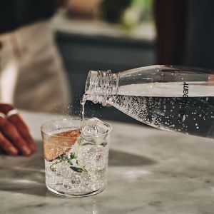 Nalewanie wody gazowanej do szklanki drinkówki - tytułowa.